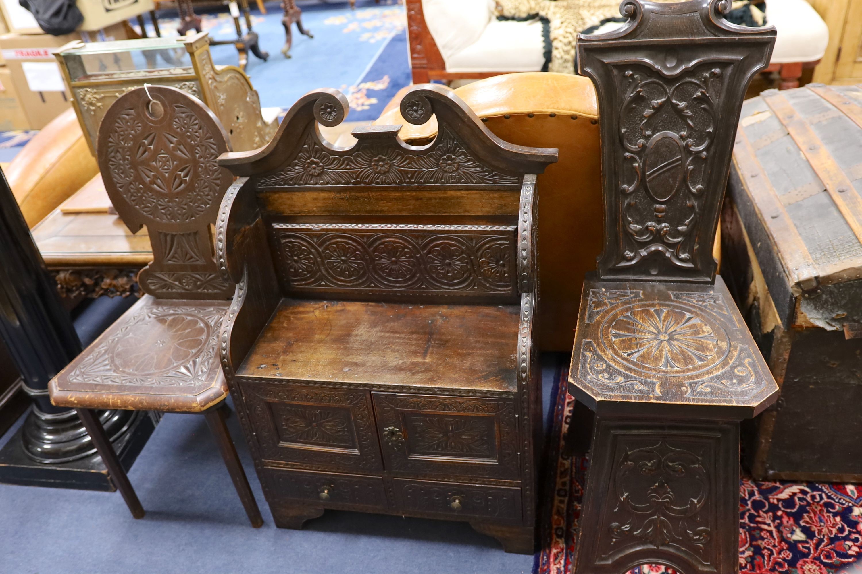 An early 20th century carved oak hall seat, width 64cm, depth 28cm, height 88cm together with two similar hall chairs